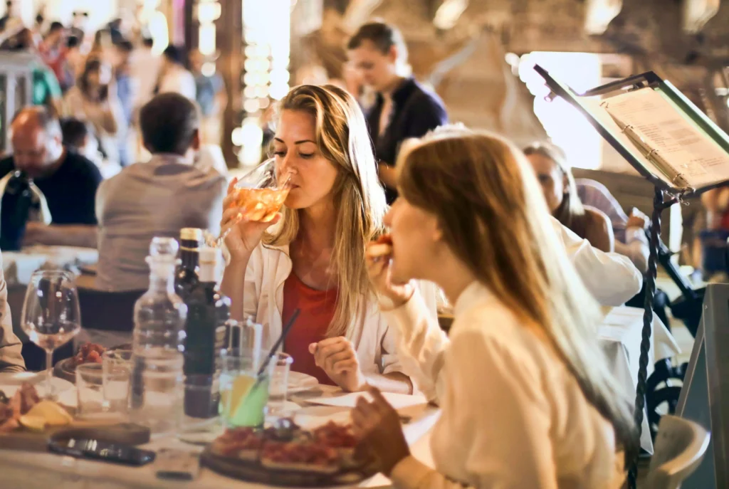 a group of women sitting at a table drinking from a glass